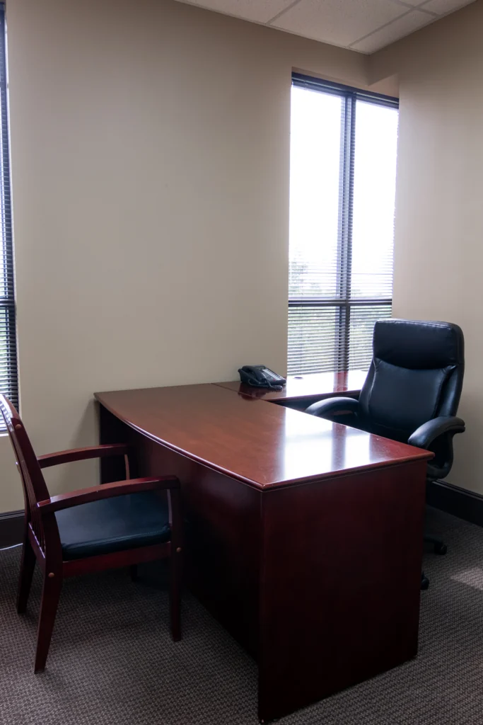 Private office with wood desk, executive chair and window blinds